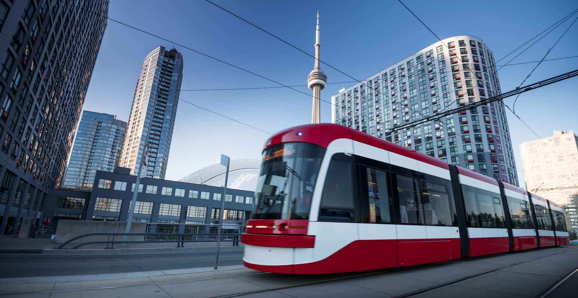 Rot-weiße Straßenbahn fährt durch die Innenstadt von Toronto mit CN Tower im Hintergrund