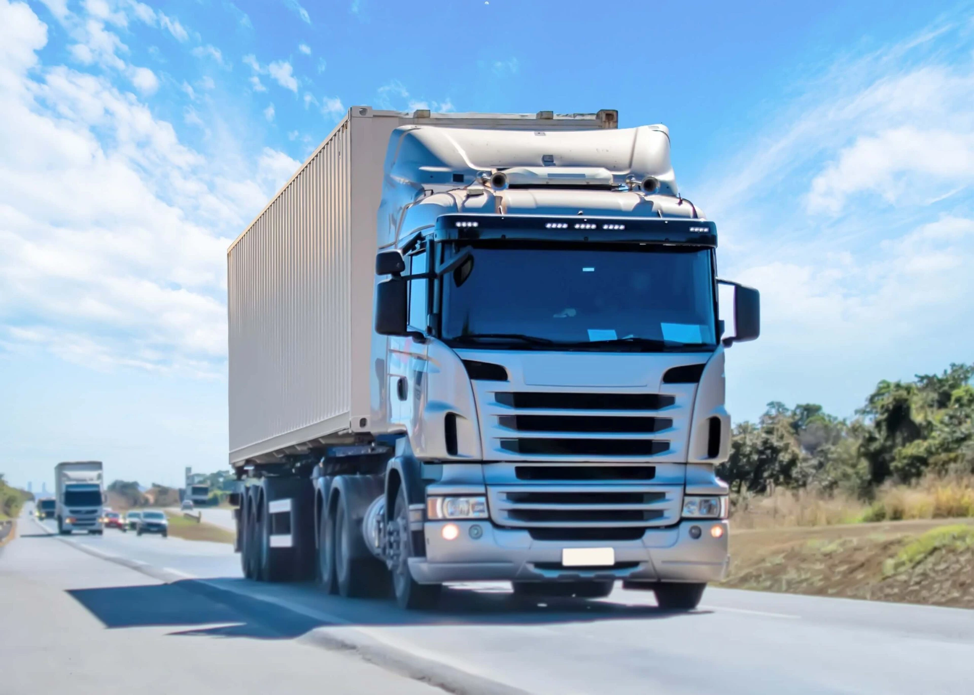 Weißer Sattelzug mit Containerauflieger fährt auf einer Autobahn bei blauem Himmel